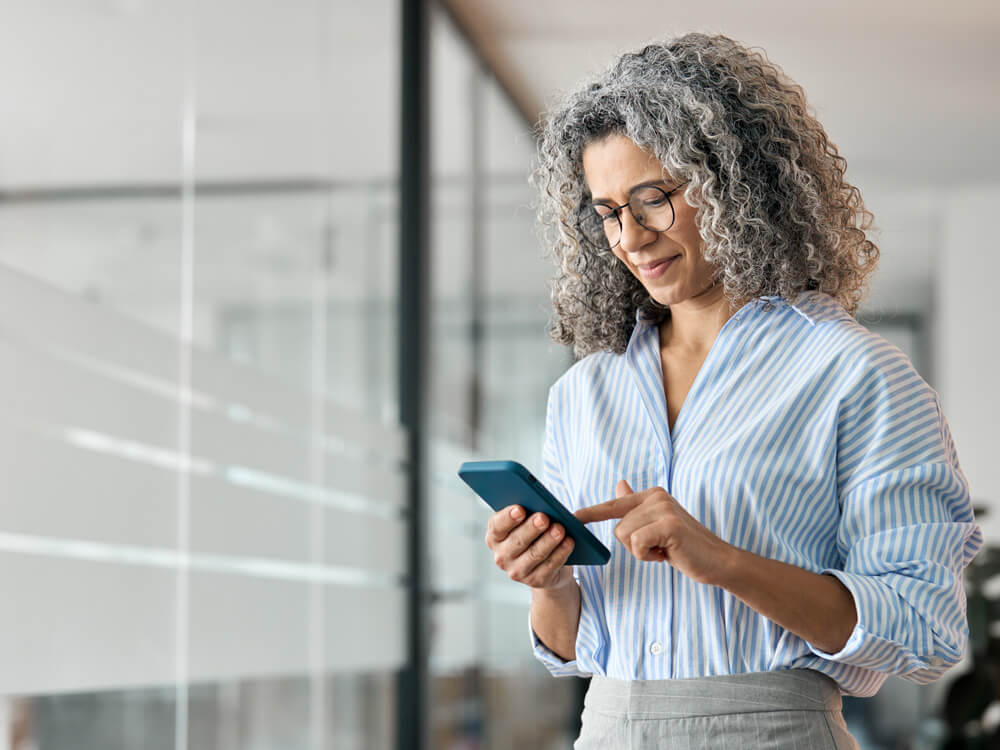 Business woman holding mobile using cellphone in office.